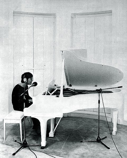 John Lennon playing his white piano.