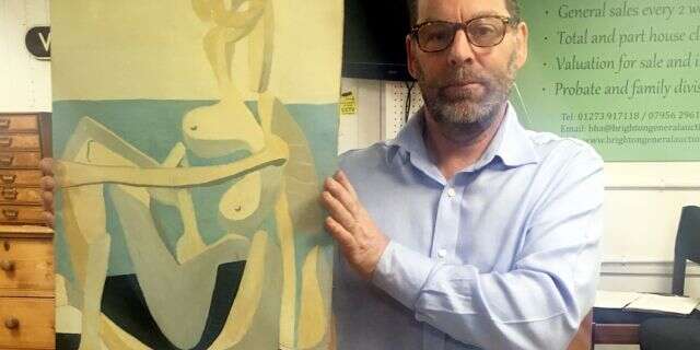 Andrew Potter, owner and auctioneer, holding the Picasso painting