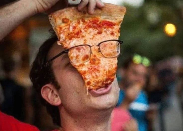 man eating a pizza with his glasses on