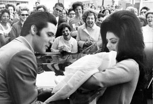 Elvis stares at Lisa Marie while Priscilla smiles down at her. 
