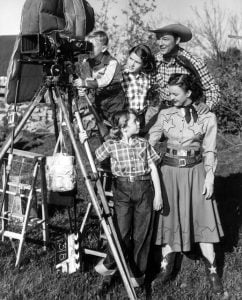 Roy Rogers, Dale Evans, and their children posing next a camera