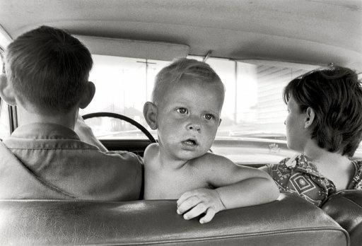 Child in the front seat of a car in the '60s.
