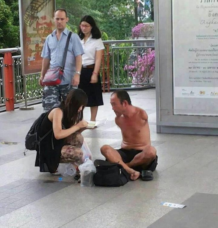 woman helps armless man with food
