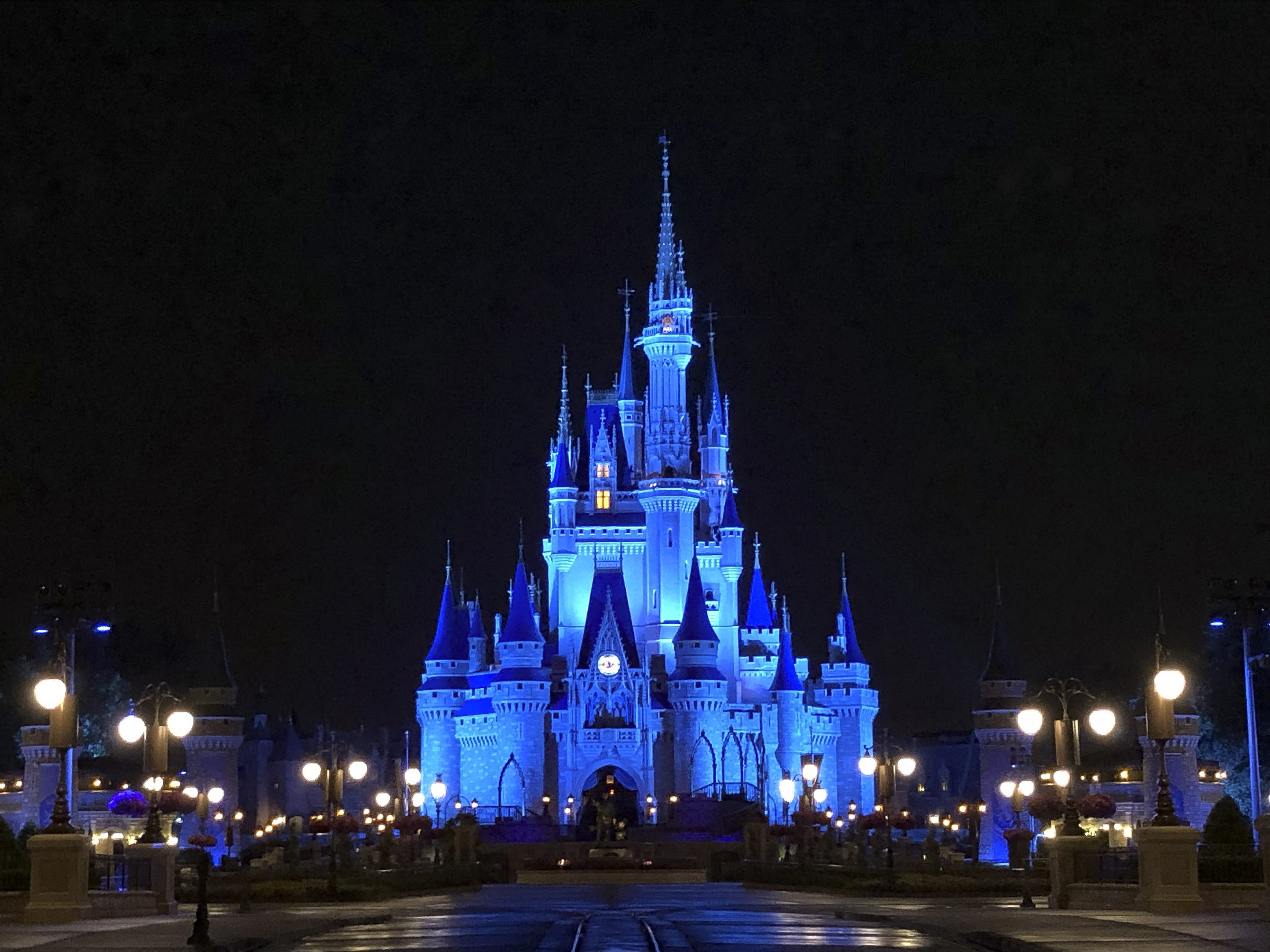 disney cinderella castle lit up in blue 