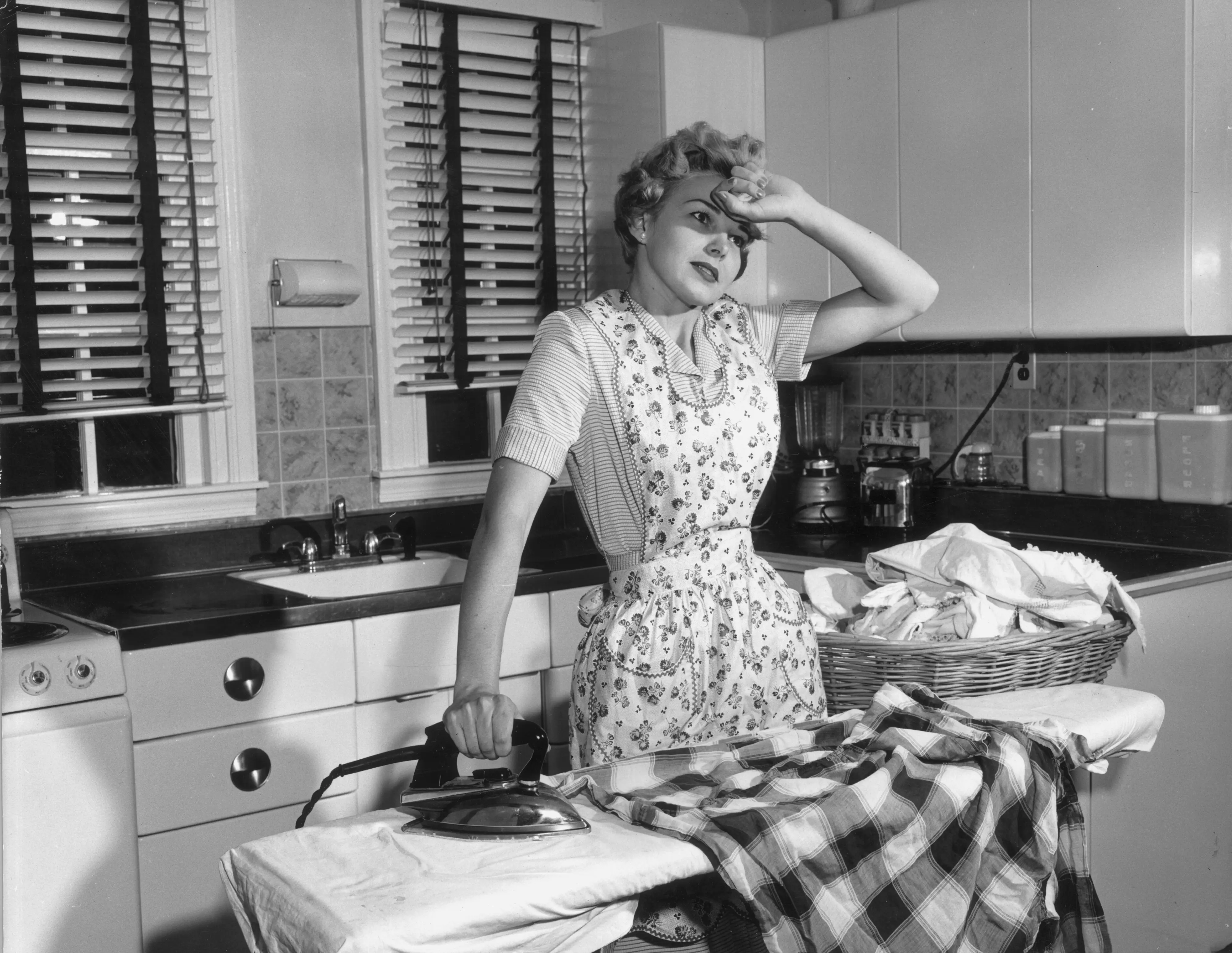 tired housewife in the 1950s ironing laundry 
