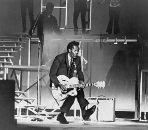 Chuck Berry (b. 1926) on stage, playing guitar. 