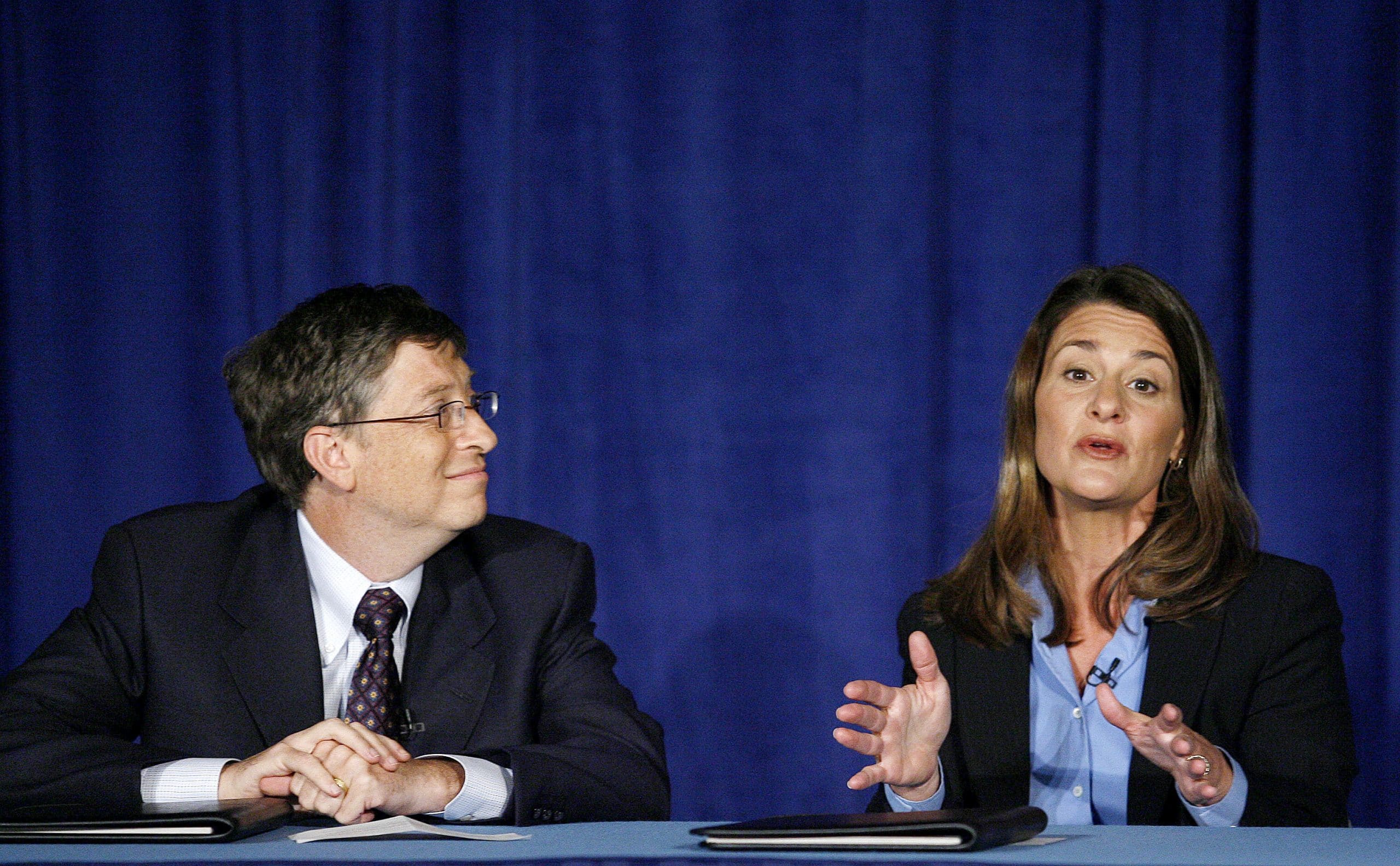 Bill Gates listens in while his wife Melinda Gates takes a question