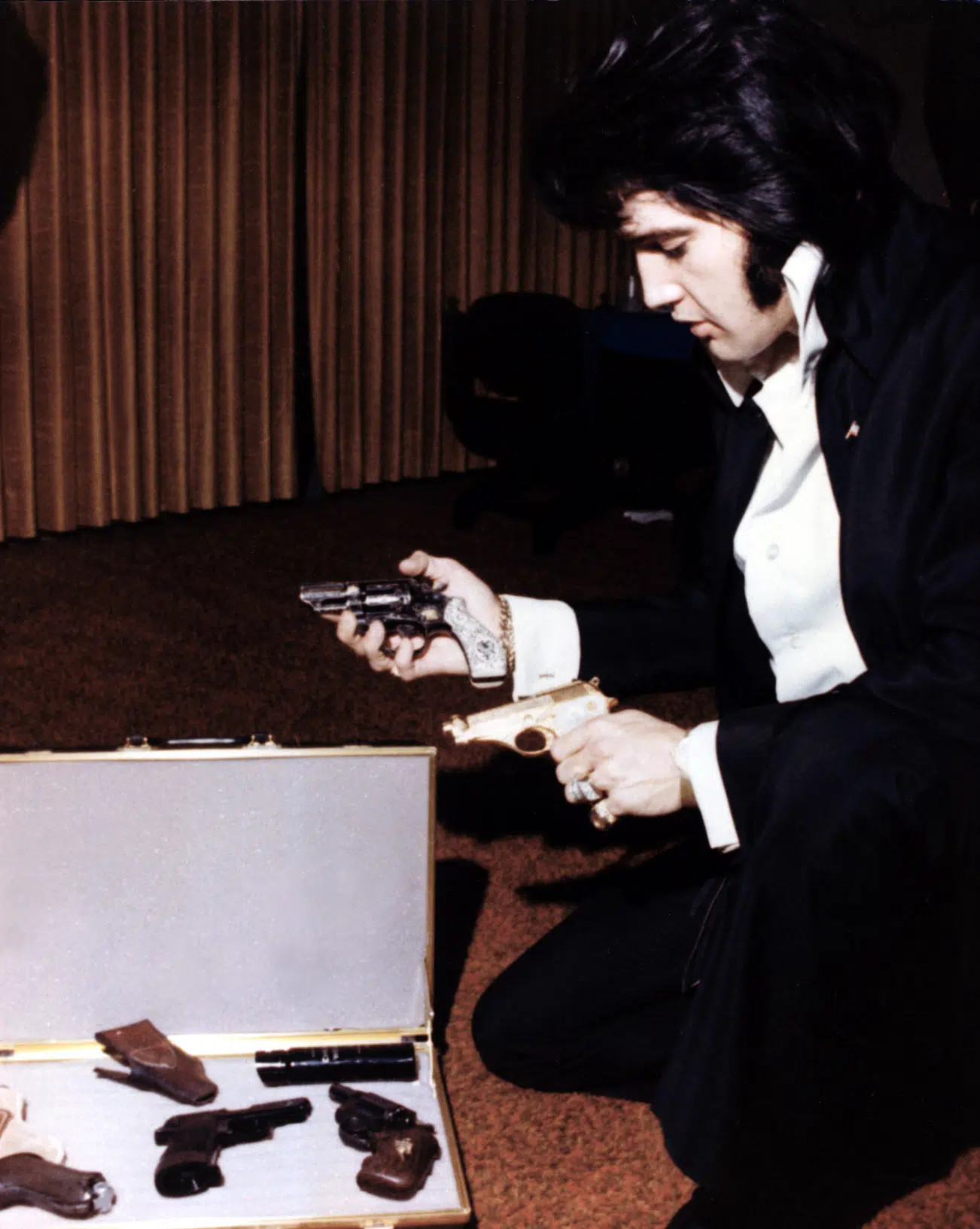 ELVIS PRESLEY examines a collection of guns