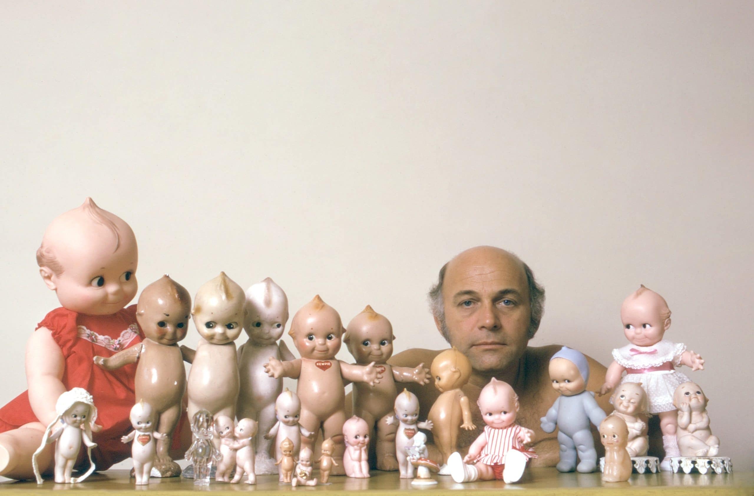 Gavin MacLeod posing with a collection of Kewpie Dolls