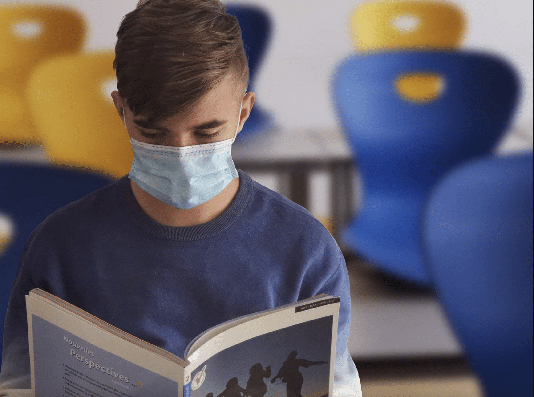 Student reads a book in school with mask on 