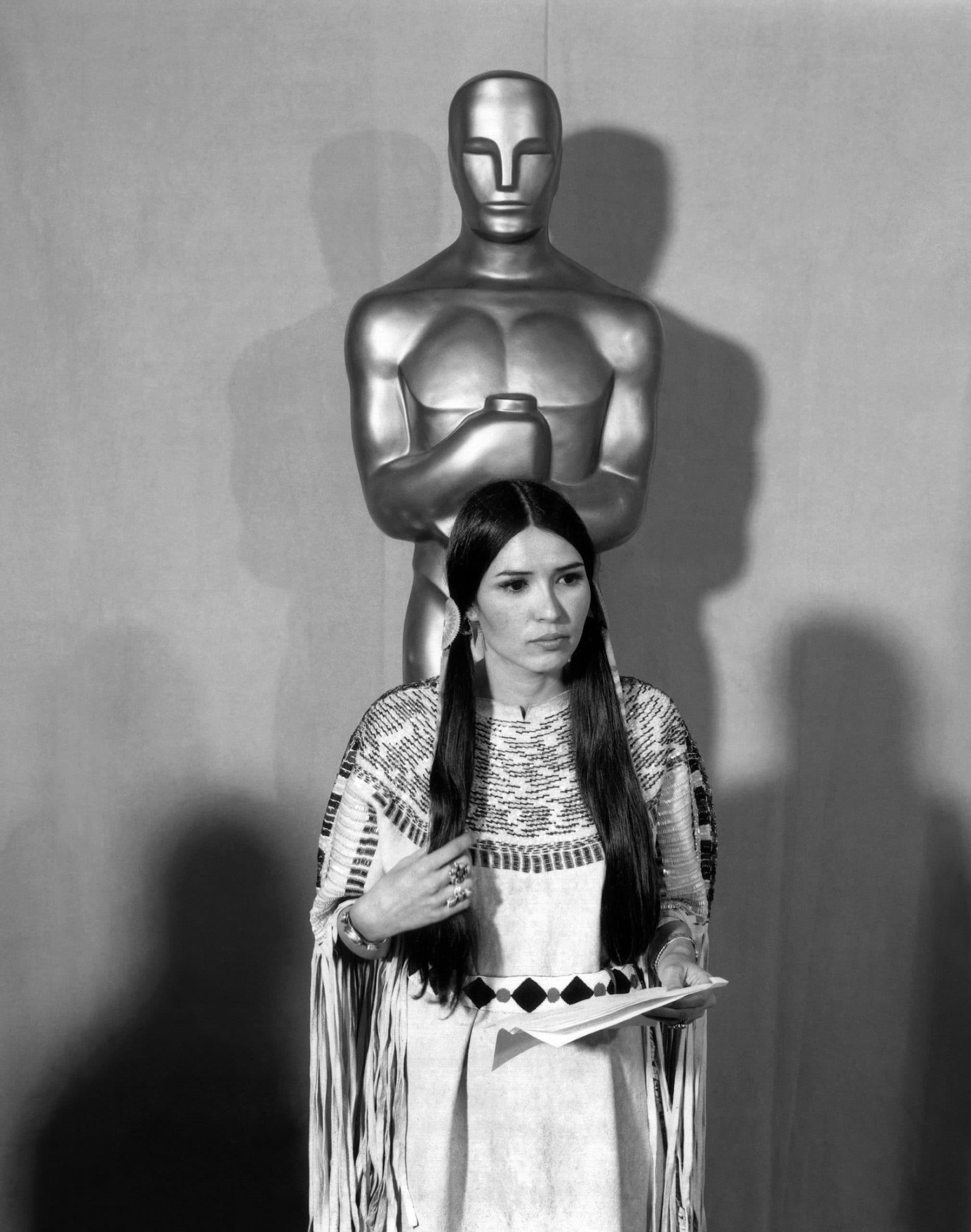 Sacheen Littlefeather holding Marlon Brando's speech refusing to accept his Academy Award for THE GODFATHER in front of a statue of the Academy Award, 1973
