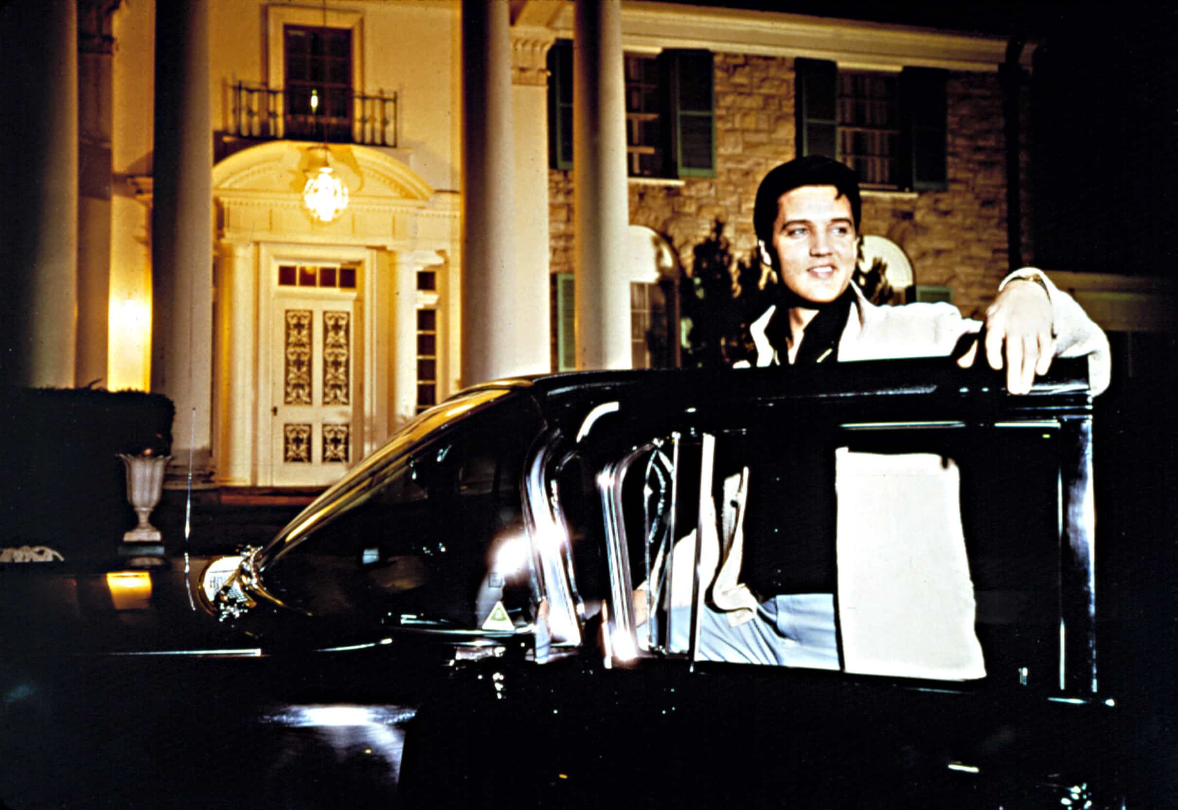 ELVIS PRESLEY, getting into his Cadillac car, in front of Graceland, circa early 1960s