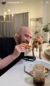 John Travolta takes a big bite out of pizza while Peanut enjoys some cheese