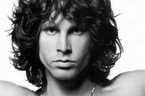 Black-and-white portrait of Jim Morrison with tousled hair, intense gaze, and bare shoulders.