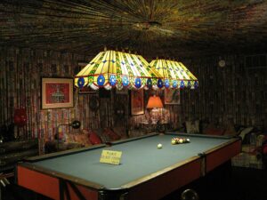 Graceland’s game room with Elvis Presley’s pool table, surrounded by vibrant fabric-covered walls and eclectic 1970s decor.