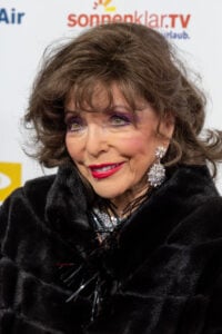 Joan Collins attends a red carpet event in elegant attire, showcasing her timeless glamour