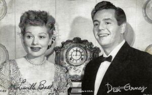 Lucille Ball and Desi Arnaz smiling together in a black-and-white promotional photo for I Love Lucy